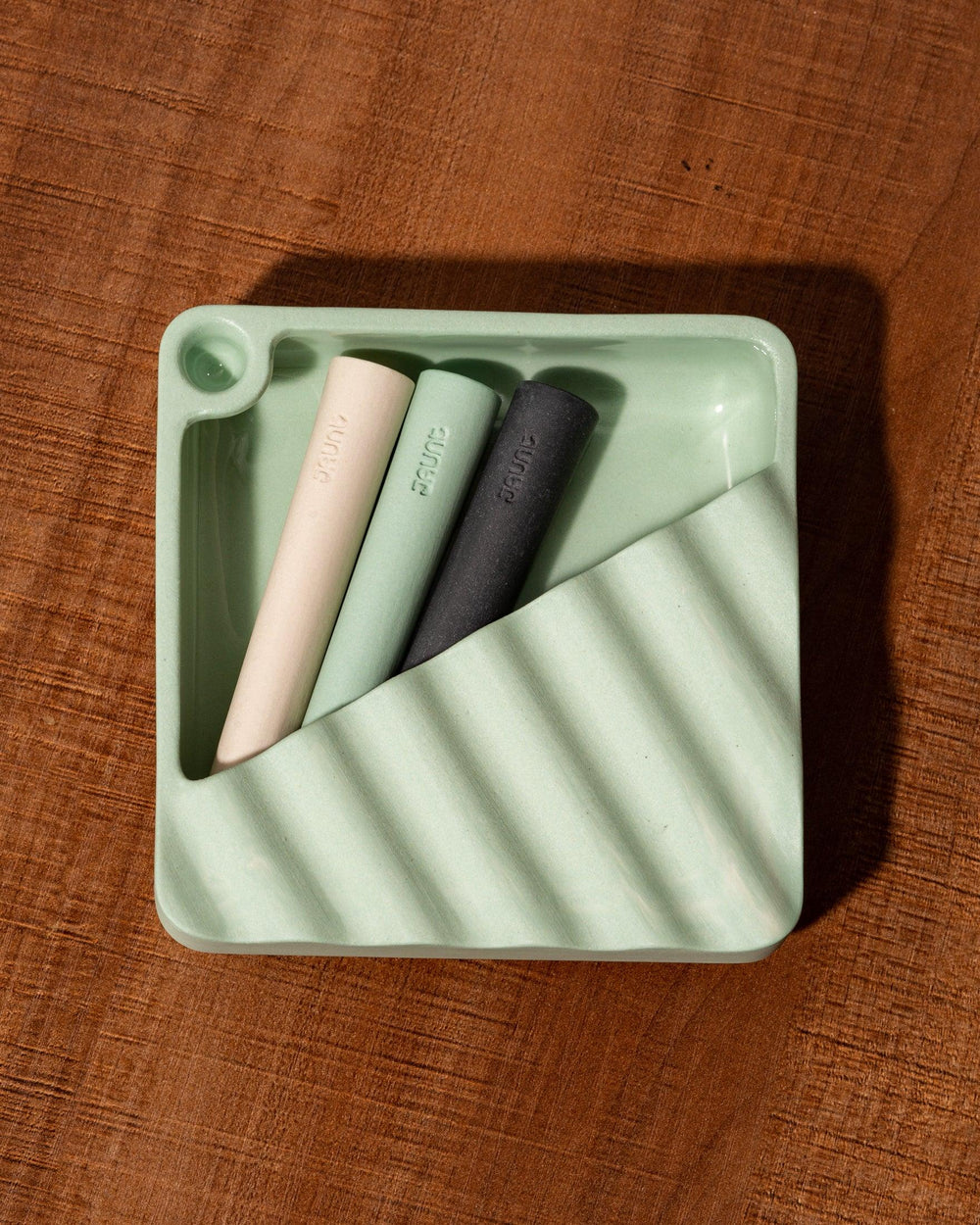 Ceramic one hitter pipes nested in a ceramic ashtray.
