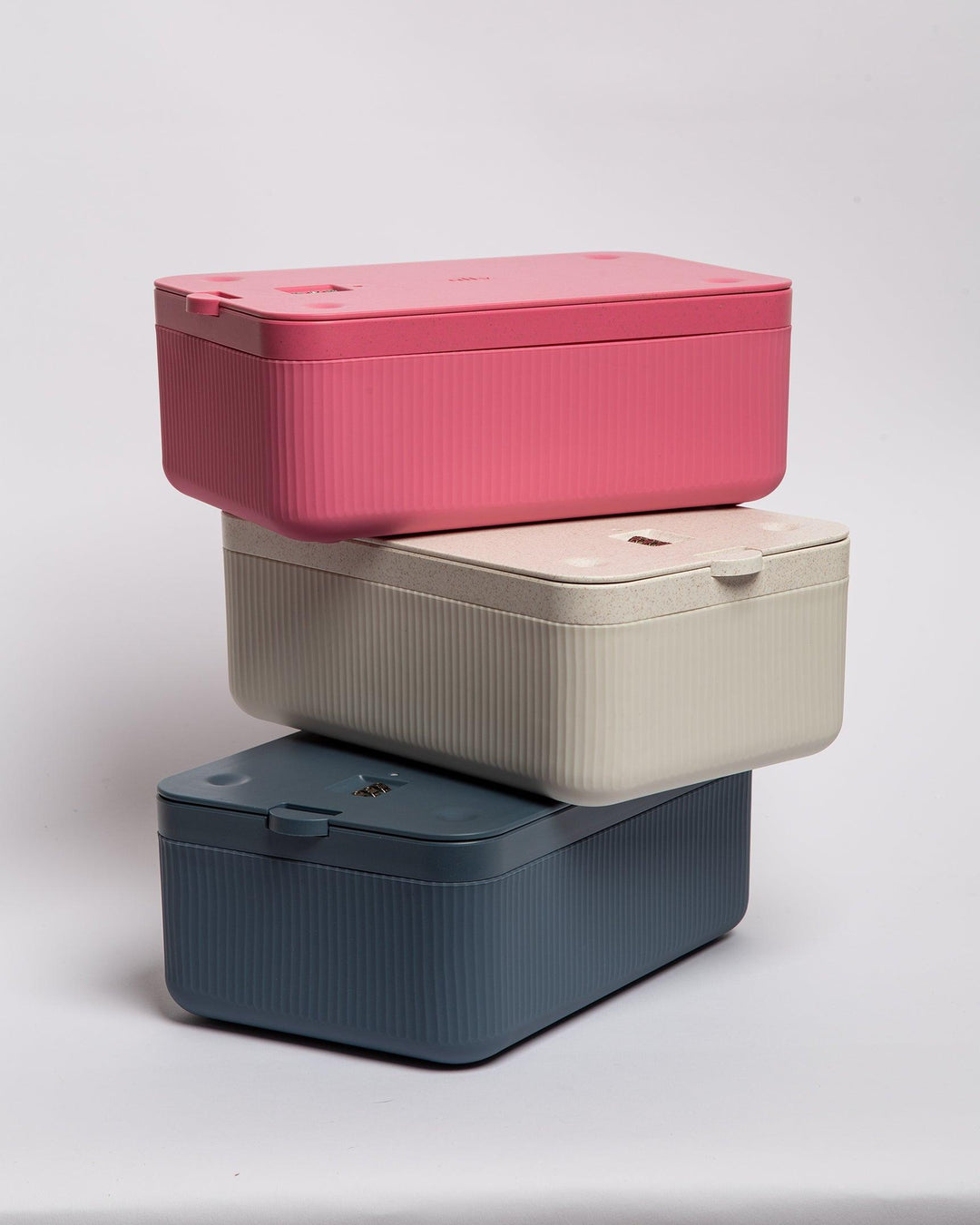 Three different colored stash boxes stacked on top of each other- pink, white, and navy.