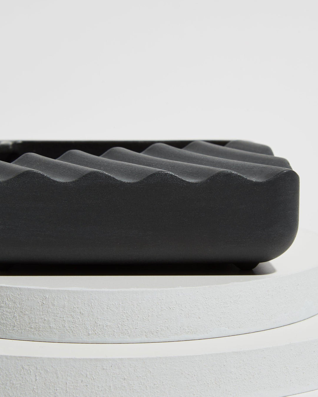 Detail of wavy design of handmade ceramic ashtray in slate black.