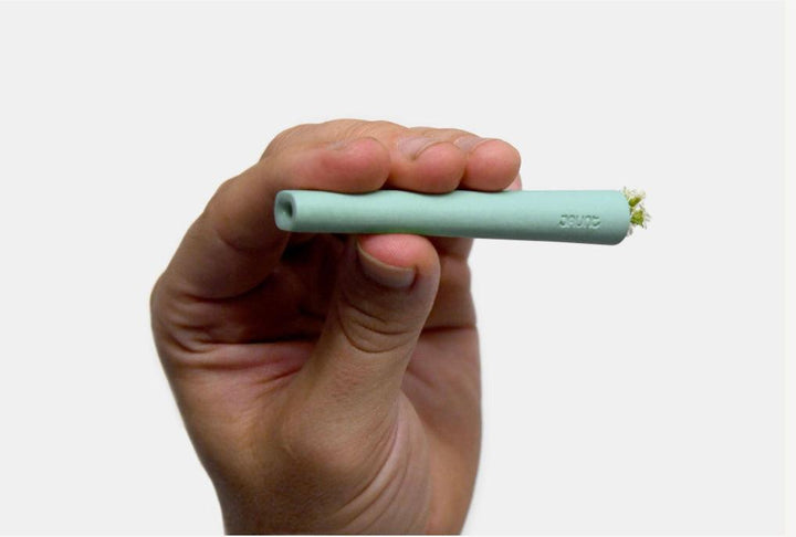 Male holding mint jaunt ceramic one-hitter with flower.