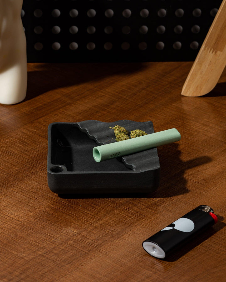 Mint Green Ceramic one-hitter resting on top of a black ashtray.